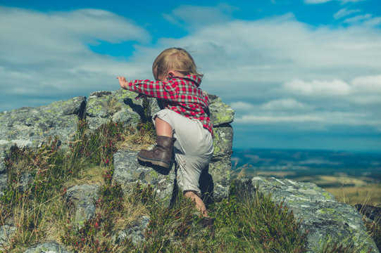 Little toddler climbing rock on the moor