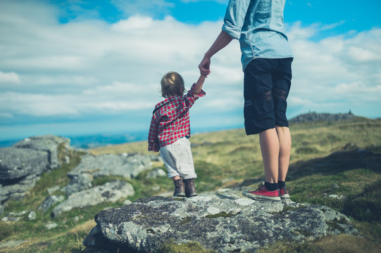 Young mother and toddler admiring view from rock on hill