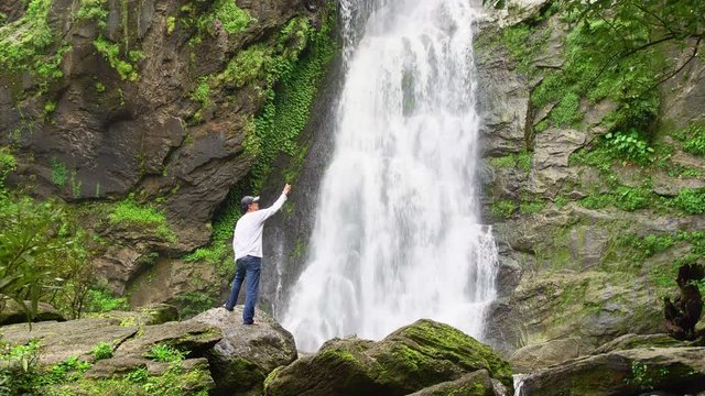 Man relaxing with freedom beautiful waterfall in the national park forest at Khlong Lan Waterfall, Kamphaeng Phet Thailand.