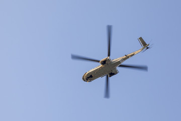 Transport helicopter in flight, with big propeller blades seen from below against Blue sky. Empty...