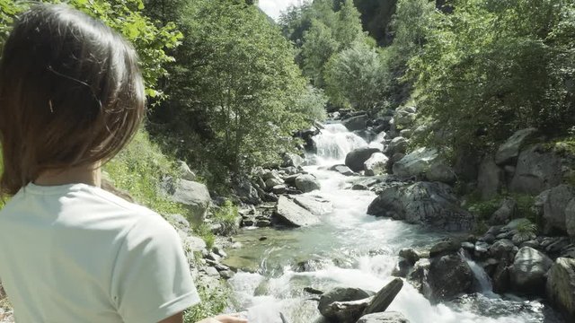 Standing behind a woman looking out at a waterfall on a hike in Auron, France.