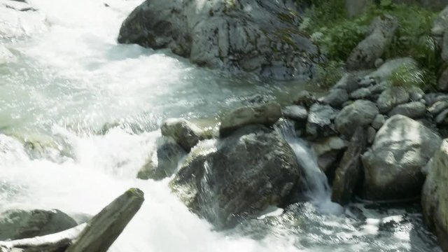 Watching a waterfall flow with blue skies and clouds in the mountains near Auron, France.