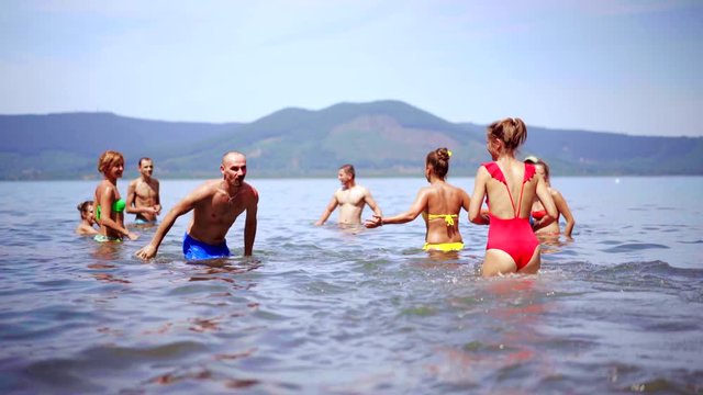 Group of Young People playing in Volleyball in the water on the sea on summer vacation. Friends fun on the beach. 4K (UHD).