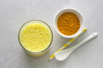 Golden milk with turmeric in a glass on a gray stone background. healthy natural energy drink. selective focus