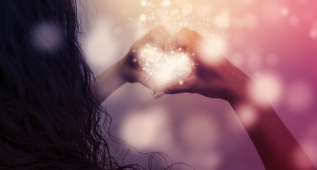 Magic emanating from the hands of a woman, a light effect in the form of hearts in the hands, glare...