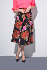 female in long floral skirt with black shoes on gray background