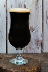 A glass of cold dark beer on wooden table - closeup with selective focus