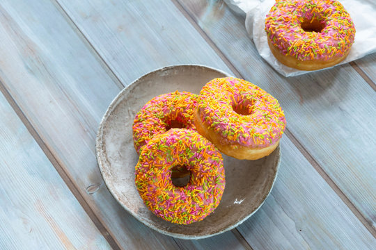 Doughnuts with colorful frosting on wooden table - top view