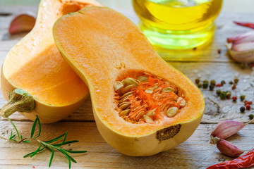 Raw organic butternut squash with ingredients for cooking on a wooden table. Selective focus