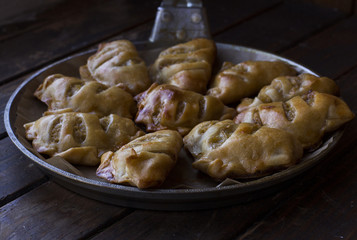 Little pies in the pan on a dark wood background.  Homemade cake.