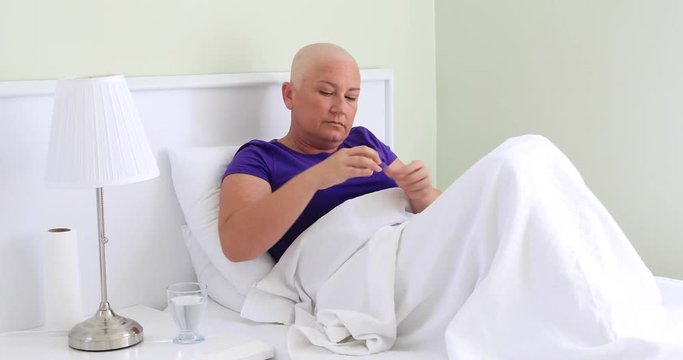 Middle aged woman cancer with cancer taking pill in hospital room