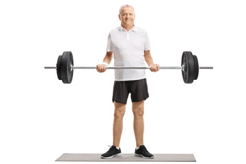 Senior standing on an exercise mat and lifting a barbell