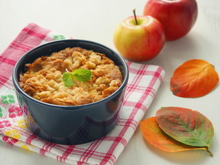 Coffee cake decorated with streusel, fresh apples, mint and bright leaves. Homemade apple pudding. Selective focus.