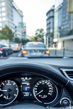 Concept shot of traffic jam in the city with close-up of steering wheel and blurred cockpit and streets with car during slowing down
