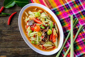 Som Tam (Spicy Papaya Salad) with salted crab, on wooden table ( Thai food)