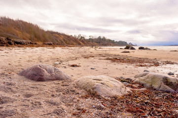 Big Rocks On Sandy Beach In Cloudy Winter Storm