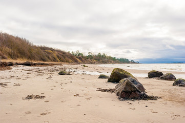 Big Rocks On Sandy Beach In Cloudy Winter Storm