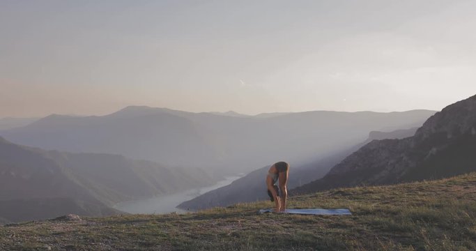 Fit young girl practicing yoga at sunset