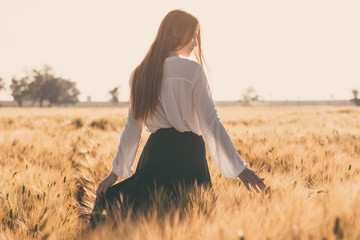Red-haired girl in a wheat field at sunset.