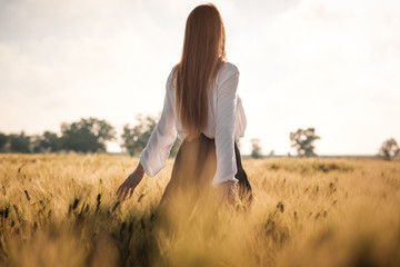 Red-haired girl in a wheat field at sunset.