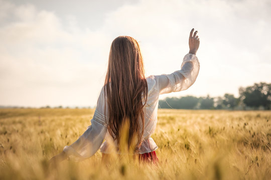 Red-haired girl in a wheat field at sunset.