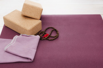Open yoga mat with two cork  blocks  and mala beads on white  background in yoga study center. Start yoga practice concept. Copy space.