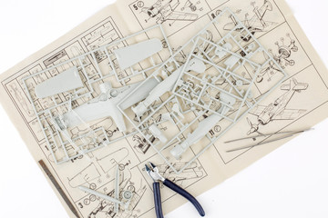 kit for assembling gray plastic airplane model on white bsckground
