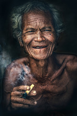 Asian men look and smile at camera. In the hands have a cigar and smoke out.