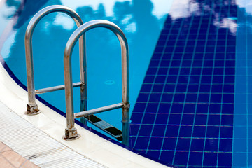 Fototapeta na wymiar Swimming pool with blue water and sunny reflections and stairs at the hotel.
