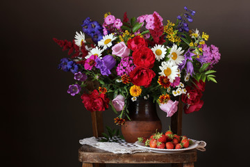 Bouquet of cultivated garden flowers and strawberries.
