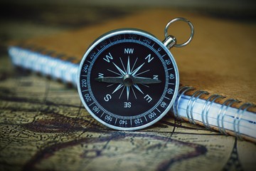 Fototapeta na wymiar Compass and notebook on blur vintage world map, journey concept