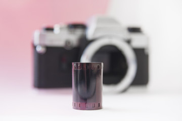 35 mm Negative Film Roll on Blurry SLR Camera Background