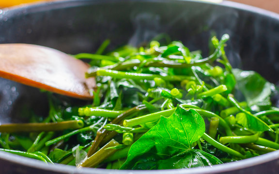 Hot and fresh Pad Pak-boong,Stir-Fried Swamp Cabbage with Salted Soya Bean, a famous Thai and Chinese's food in a cooking pan.