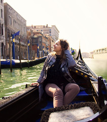 Fototapeta na wymiar young attractive happy sunny girl is sitting in gondola on Grand canal background in Venice and smiling