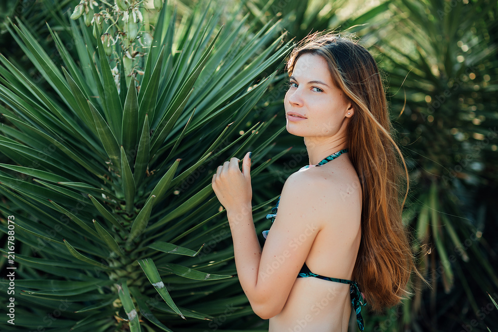 Wall mural portrait of a beautiful girl in a swimsuit near palms