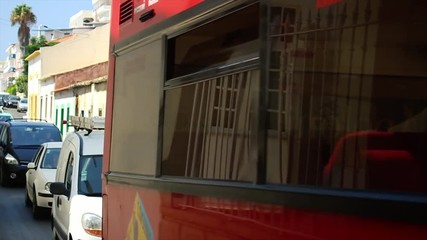 Red open tourist bus passing and windows reflecting.