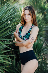Portrait of a beautiful girl in a swimsuit near palms