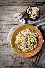 Italian pasta fusili with mushrooms and cream sauce on wooden table, copy space, top view. Autumn Food Concept