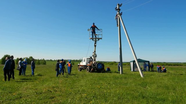 motion to workers installing electrical lamp post among green grass