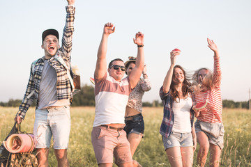 Obraz premium Happy young friends having picnic in the park.They are all happy,having fun,smiling and playing guitar.