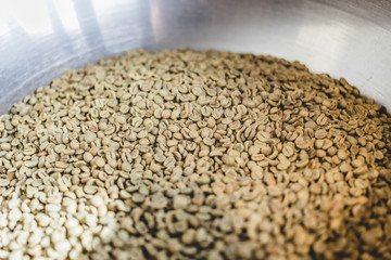 Obraz premium Green raw coffee beans in metal cylinder