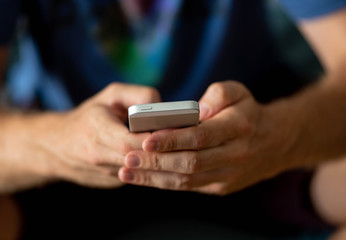 close-up of man hands holding a smart cell mobile phone in a over use of technology concept.
