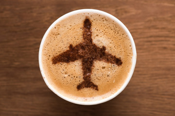 top view of cup of coffee with plane sign on wooden tabletop, traveling concept