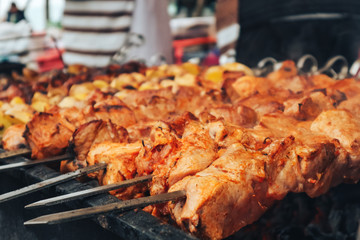 Meat baked on the grill with potatoes. Meat delicacies. Sausages homemade sausages on the grill. Street food. Homemade sausage. Pickles and salads. Festival of street food and meat.