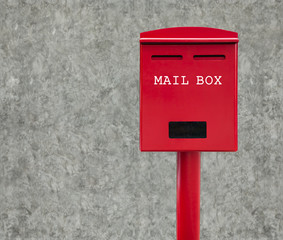 Red mail box with cement wall as background