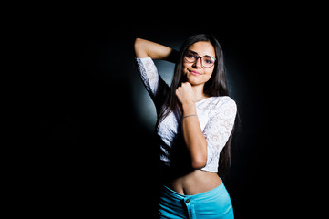 Fototapeta premium Portrait of an attractive young woman in white top and blue pants posing with her glasses in the dark.