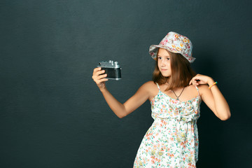 beautiful smiling child (girl) with white teeth holding a camera and making selfie