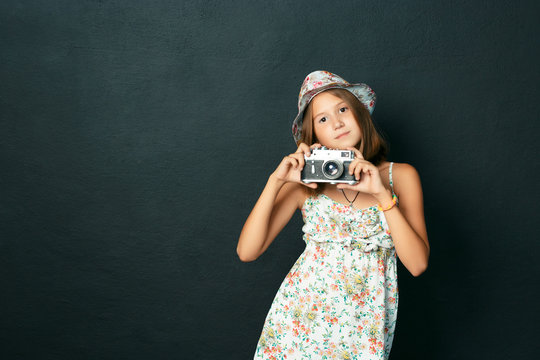 beautiful smiling child (girl) with white teeth holding a instant camera