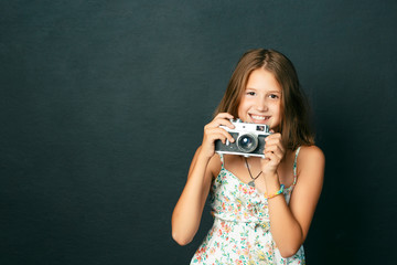 beautiful smiling child (girl) with white teeth holding a instant camera