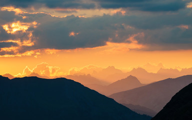 Fototapeta premium The Alps at sunrise. Colorful sky majestic mountain peaks, fog mist valleys. Sunburst and backlight expansive view from above.